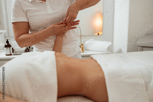Masseuse massaging woman hand in spa salon