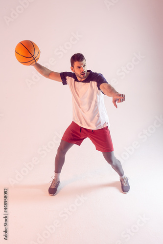 Young european sportsman play basketball in studio