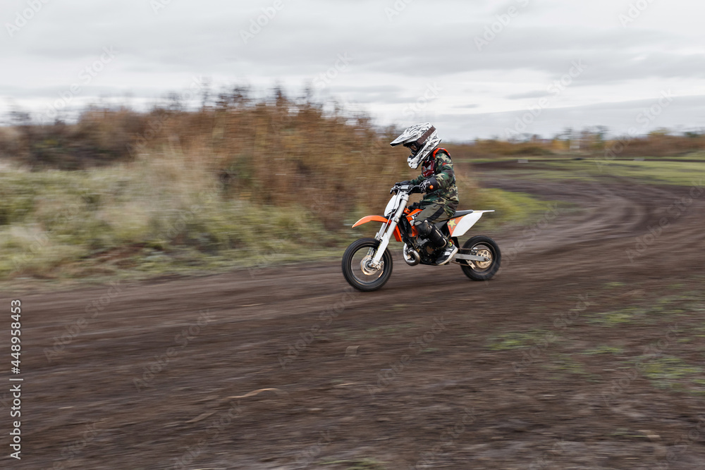 Child on his small motorcycle. Small biker dressed in a protective suit and helmet. The kid is engaged in motocross.