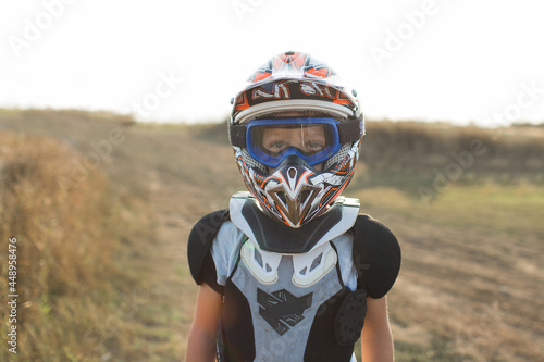 Child rider on motorcycle. Small biker dressed in a protective suit and helmet. The kid is engaged in motocross