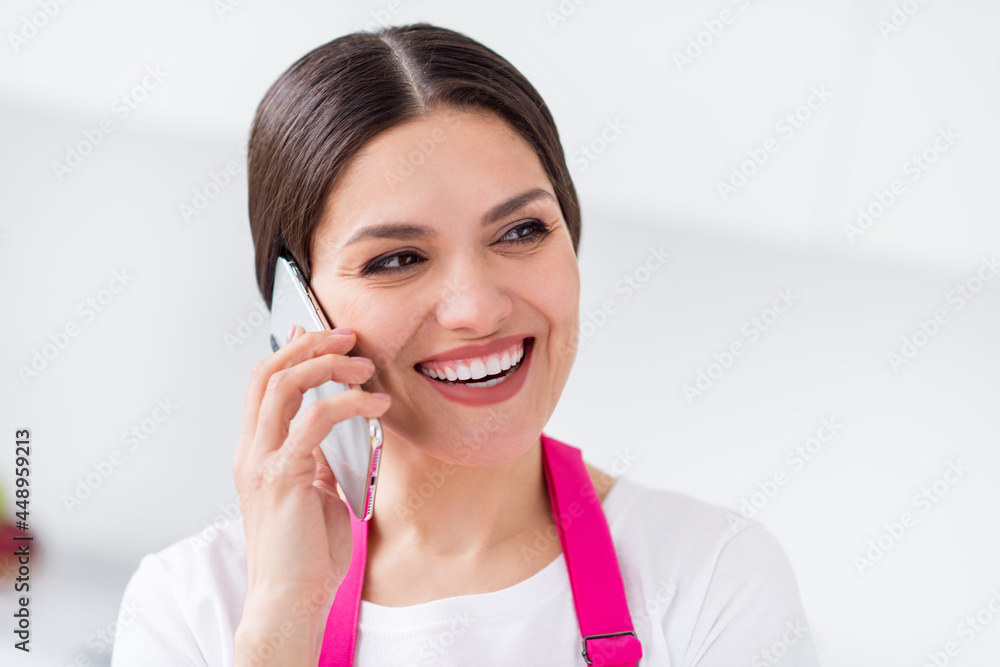 Photo of funny positive young lady wear pink apron talking modern gadget cooking dinner smiling indoors room home house Photo of funny positive young lady wear pink apron talking modern gadget cooking dinner smiling indoors room home house
