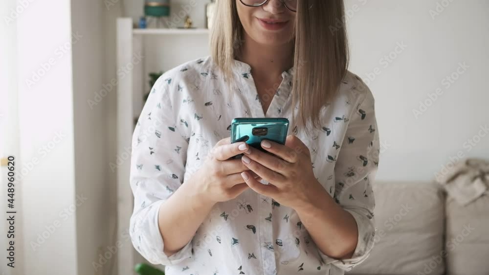 Woman with eyeglasses texting message and using mobile phone, smiling at home Woman with eyeglasses texting message and using mobile phone, smiling at home