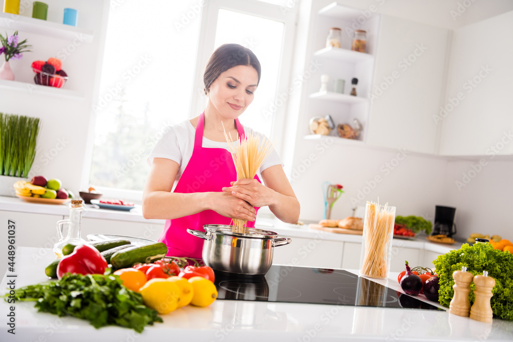 Photo of optimistic brunette millennial lady cook pasta wear apron from home at table kitchen