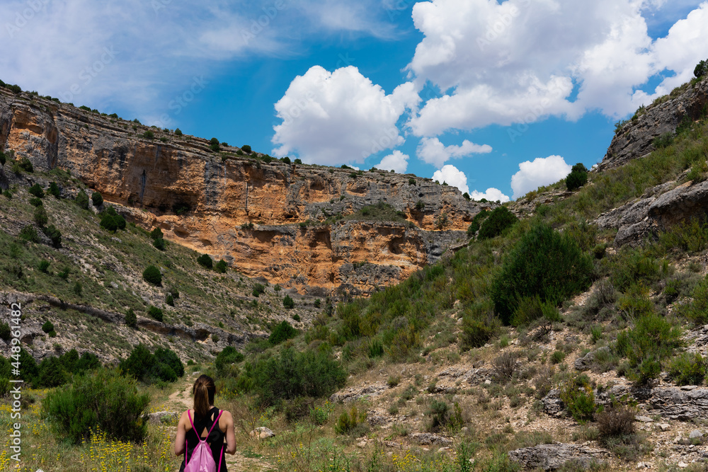 A young woman walks through nature in a mountainous area, and observes a spectacular blue sky.