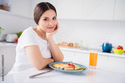 Photo of sweet dreamy mature woman dressed white t-shirt eating dinner smiling arm chin indoors house home room