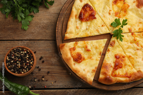 Delicious khachapuri with cheese on wooden table, flat lay photo