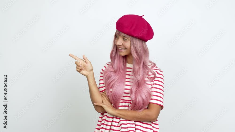 Young woman with pink hair pointing finger to the side and presenting a product over isolated background Young woman with pink hair pointing finger to the side and presenting a product over isolated background