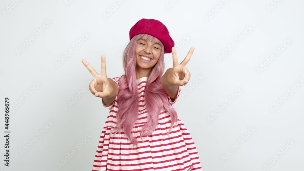 Young woman with pink hair smiling and showing victory sign with a cheerful face over isolated background Young woman with pink hair smiling and showing victory sign with a cheerful face over isolated background