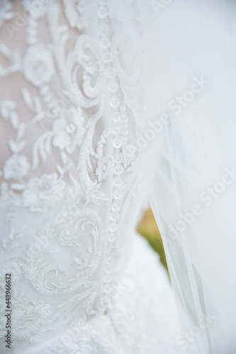 Gentle picture of a bride standing from behind. Close up of bride dress. White lace dress.