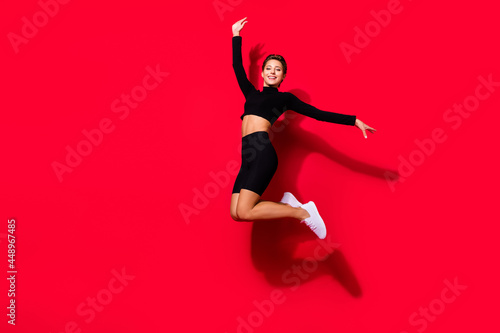 Photo of dreamy sportive charming lady jump raise hands wear black cropped top isolated red color background