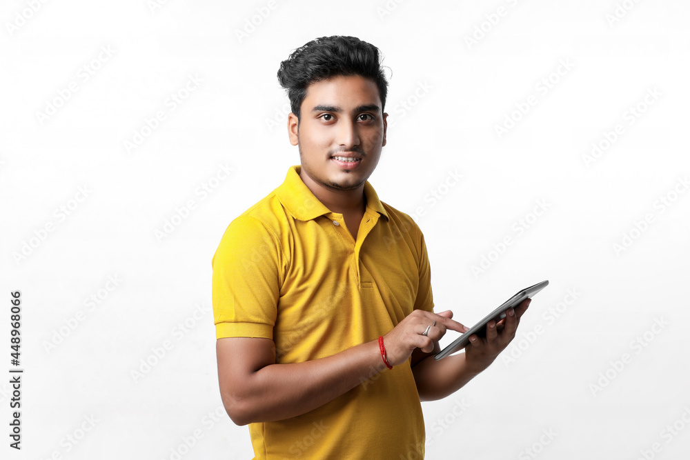 Young indian college student using tablet over white background. Young indian college student using tablet over white background.