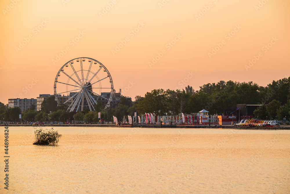 2021.07.23. Hungary, Siofok. Sunrise landsacpe in the lake Balaton. Included with Ferris wheel and Plazs beach. Amazing golden hour colors. It is hotels on the background