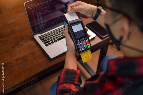 Man sitting at a table making a contactless payment on a credit card reader photo