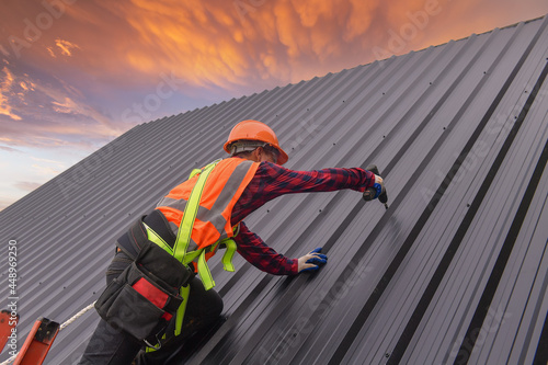 Construction worker installing metal sheets on a roof, Thailand photo