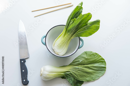 Obraz na płótnie Pak choi or boy choi with a knife next to it and some Chinese sticks over white background w salonie
