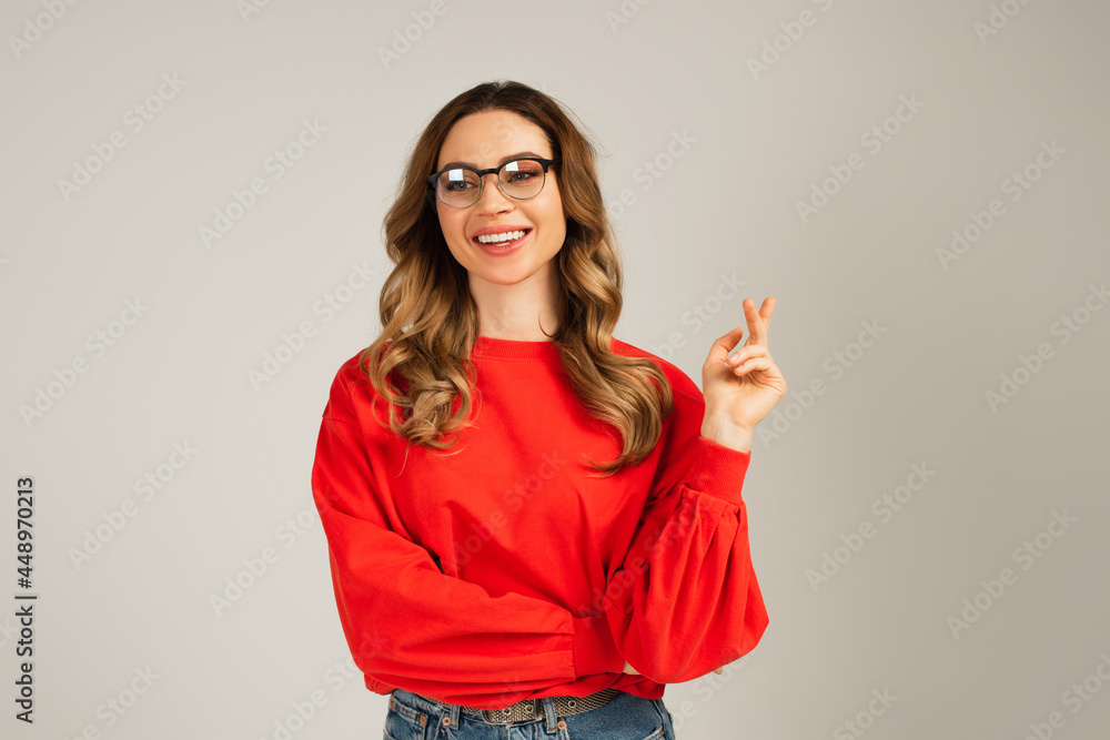 positive woman in sweatshirt and eyeglasses looking away isolated on grey positive woman in sweatshirt and eyeglasses looking away isolated on grey
