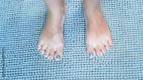The Female Feet Step on a Blue Soft Fluffy Carpet in the Bathroom. The Legs Feel Good and Comfortable on a Soft Rug.