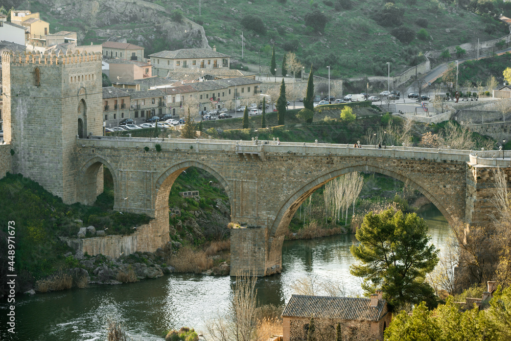 Great panoramic view at sunset of the San Martin bridge in Toledo and the Tagus river flowing calmly through its arches