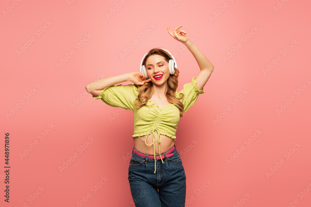joyful woman in wireless headphones dancing on pink joyful woman in wireless headphones dancing on pink