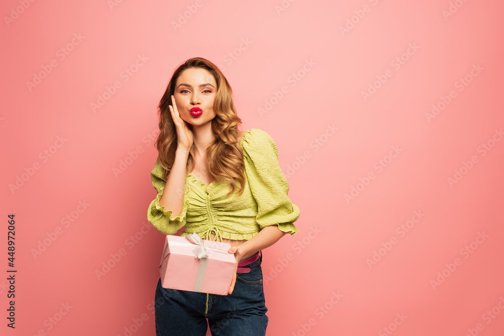 curly woman with duck face holding wrapped present isolated on pink curly woman with duck face holding wrapped present isolated on pink