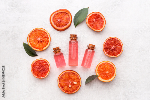 Grapefruit fragrance essential oil in bottles with fresh fruits. Top view