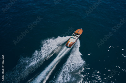 Top view of a wooden powerful motor boat. Classic Italian wooden boat fast moving aerial view. Luxurious wooden boat fast movement on dark water.