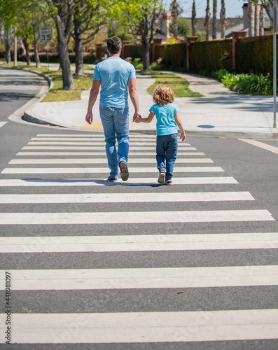 father leading his son through zebra crossing, togetherness
