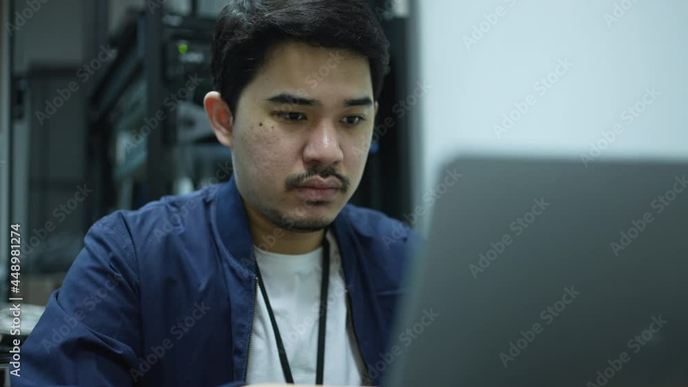 slow motion scene on network engineering man typing keyboard laptop to configure command software and check connectivity on ethernet broadband at data center operation room for technology concept