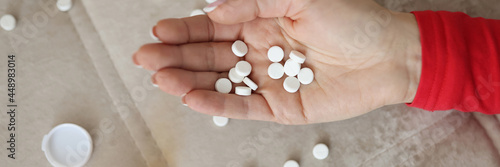 Female hand with white scattered pills closeup