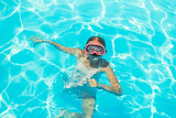 Happy girl in swimming goggles, dives under water with fun in the pool, water sports, snorkeling, family swimming lessons on summer sea