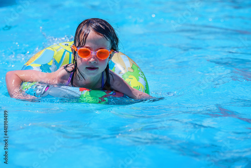 Beautiful young girl swimming in pool. Summer holiday, vacation and happy childhood concept.