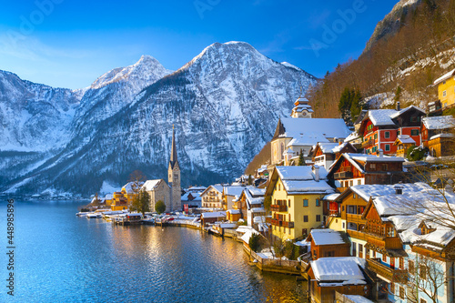 Classic postcard view of famous Hallstatt lakeside town in the Alps with traditional passenger ship on a beautiful cold sunny day with blue sky and clouds in winter, Salzkammergut region, Austria View