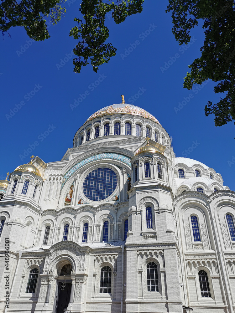St. Nicholas Cathedral among the trees against the background of a cloudless sky, on a summer day in Kronstadt. St. Nicholas Cathedral among the trees against the background of a cloudless sky, on a summer day in Kronstadt.