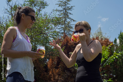 Two young women are chatting while drinking detox drinks after exercise.