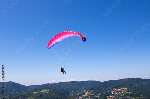 Paraglider pilot hovering over the Żar Mountain on a summer day