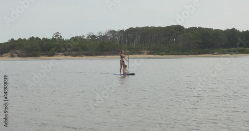 beautiful young woman and her daughter paddle boarding with a small dog