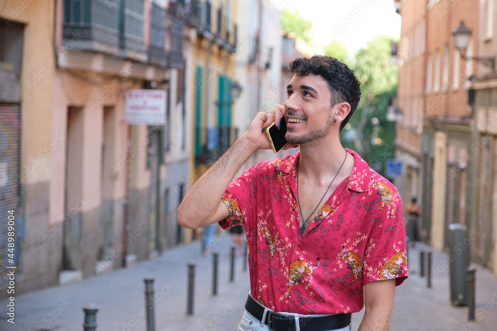 Young caucasian man with long false nails smiling and speaking on the phone. Young caucasian man with long false nails smiling and speaking on the phone.