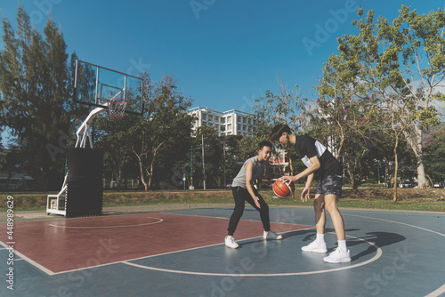 Sports and recreation concept young male teenagers practicing dribbling basketball in the court after school