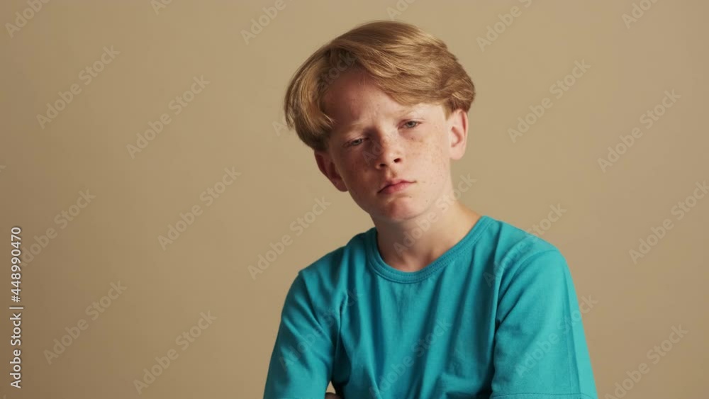 A shocked little boy is looking to the camera isolated over beige background in the studio A shocked little boy is looking to the camera isolated over beige background in the studio