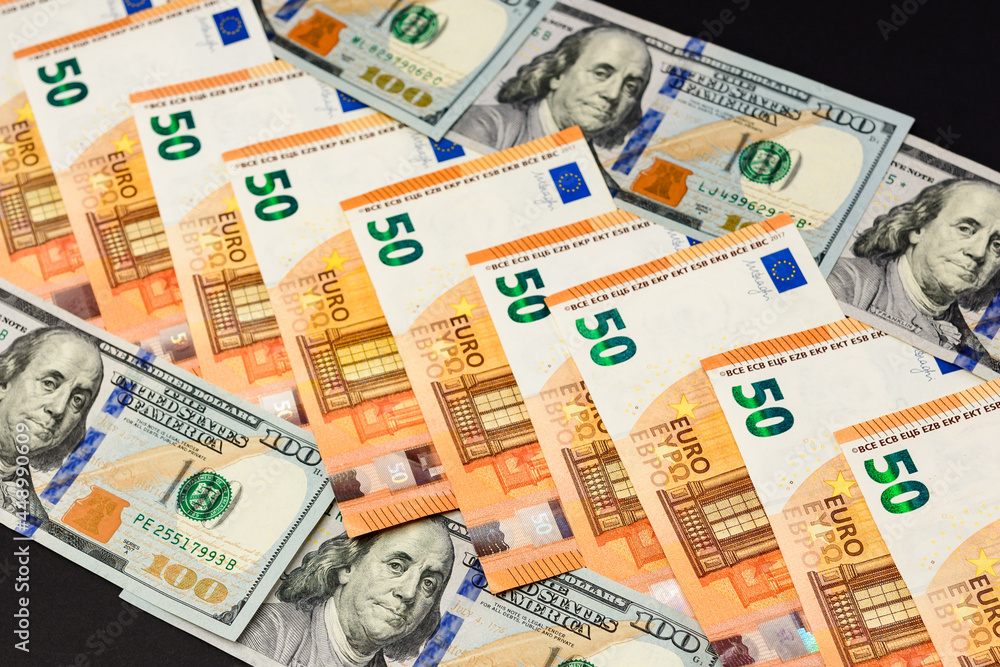 50 euros and 100 dollars lie in a row, banknotes of euro and dollars on a black background.