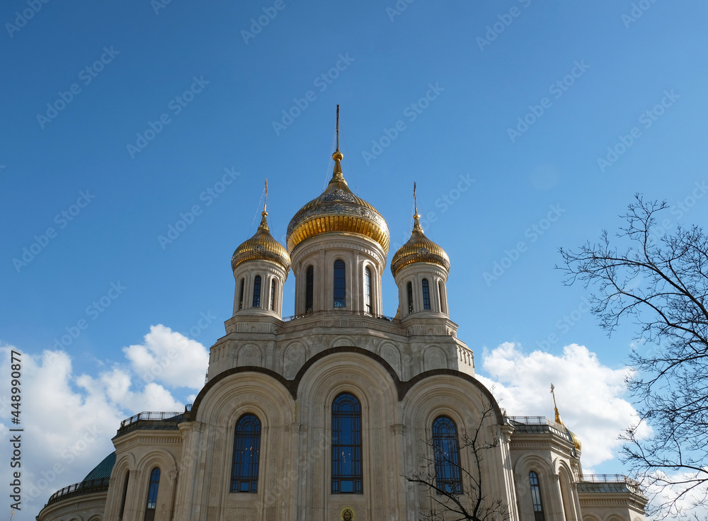 Ancient and medieval golden Domes with golden crosses on the Orthodox Church against the blue sky with clouds. Exterior facade with white walls, white stone church.