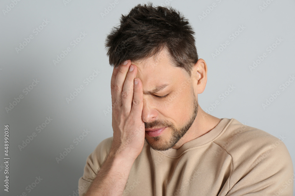 Man suffering from terrible migraine on light grey background Man suffering from terrible migraine on light grey background