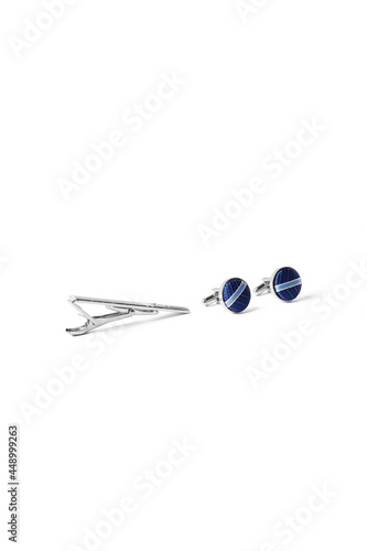 Subject shot of steel tieclip and cufflinks with blue textile surface with light stripes. Stylish accessories for office wear are isolated on the white background. photo