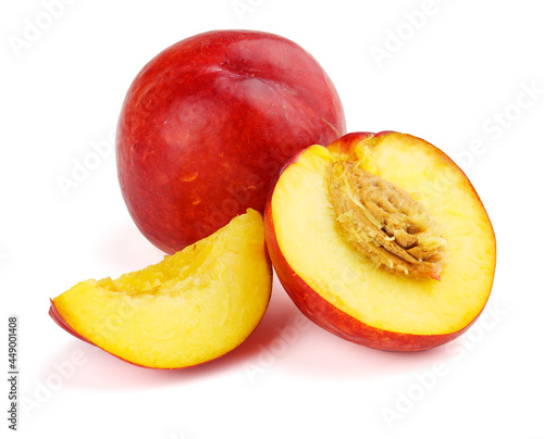 Group of nectarine fruits with slices and pits on white.