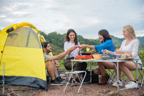 group of male and female friends set a picnic table and cooking in the midst of beautiful mountains