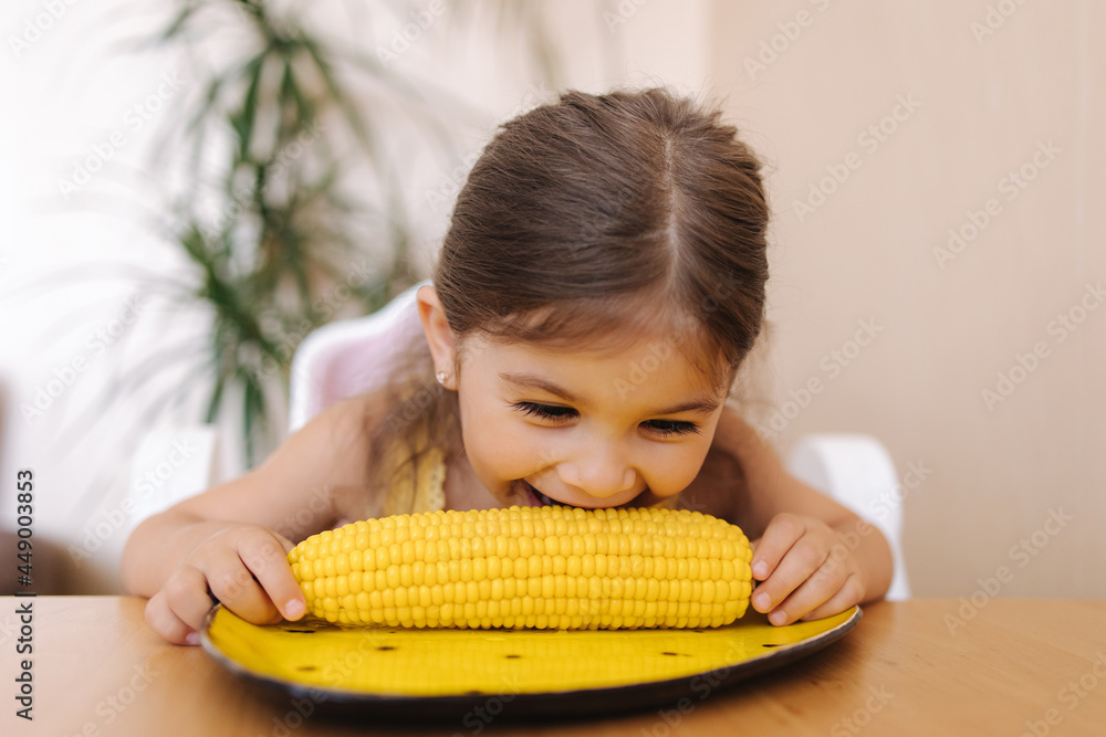 Adorable little girl eating corn at home. Cute kid tree year old eat boild corn Adorable little girl eating corn at home. Cute kid tree year old eat boild corn