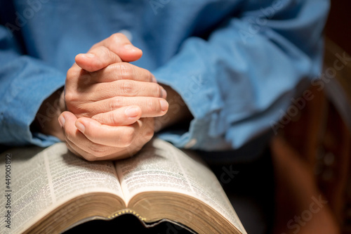 Hands folded in prayer on a Holy Bible