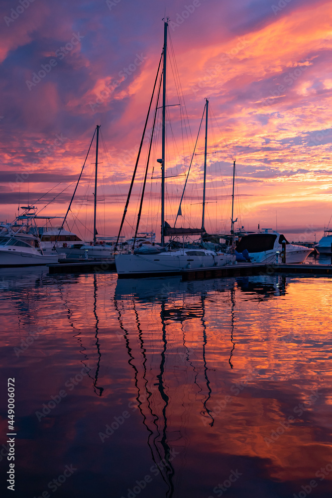 Dramatic sunset over sailboats in the calm water of marina. Travel and adventure concept 