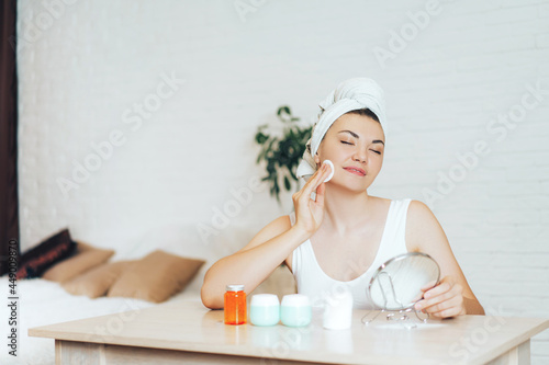 Young girl rubs her face with cotton pad