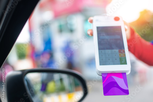 Gas station worker swipe mockup credit card via payment terminal after giving a price quote to the customer sitting in the car.